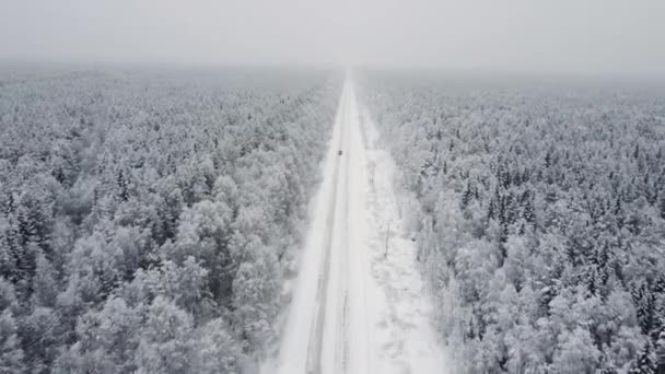 Widok z lotu ptaka z drona, widok z lotu ptaka na zimowy krajobraz i śnieżną drogę lodową, samochód poruszający się po okolicy otoczony pięknym lasem iglastym 4k — Wideo stockowe