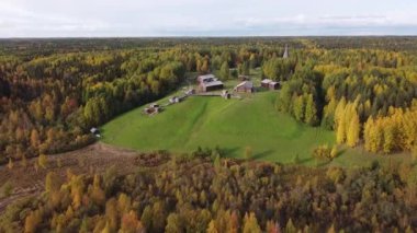 Ormandaki tepede bir köy, İHA saldırısı. Bardan tipik ahşap evler. Sıcak güneşli bir gün, yaz manzarası. Pürüzsüz yeşil çimenler, gerçek doğa