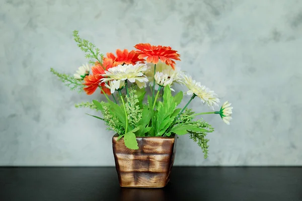 Konstgjorda blommor i blomkruka och vit vägg — Stockfoto