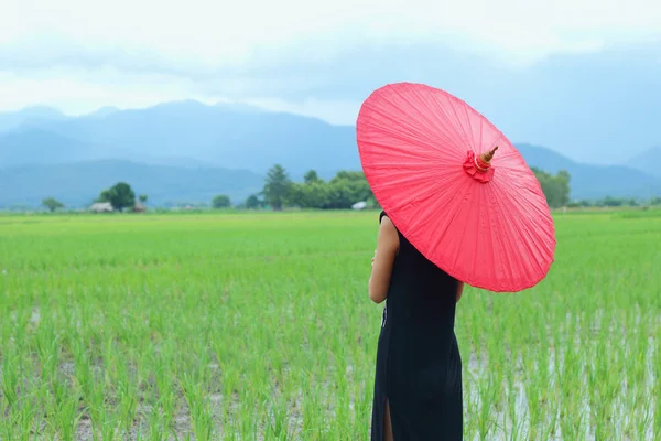 Women dressed in black with a red umbrella. — Stock Photo, Image