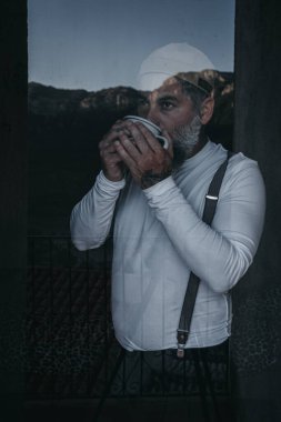 Yalnız bir adam karanlık bir odada kahve içiyor.