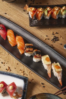 Seramik tabaklarda servis edilen masada çeşitli suşi ve nigiri çeşitleri var..