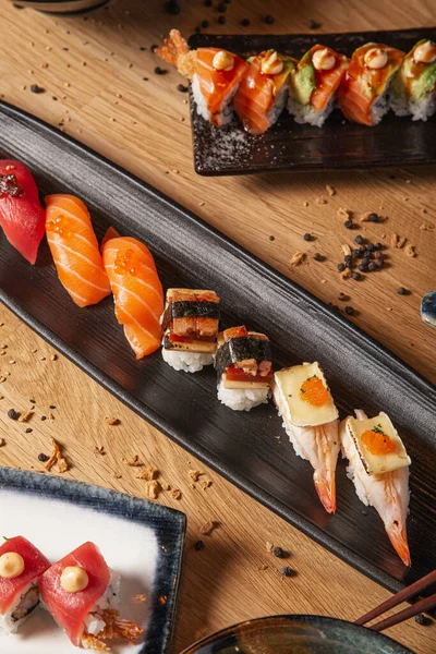 Seramik tabaklarda servis edilen masada çeşitli suşi ve nigiri çeşitleri var..
