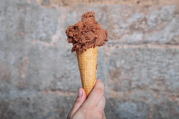 Hand holding chocolate ice cream cone. Chocolate ice cream in waffle cone
