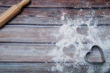 Koyu mutfak masasında un ve kalp şeklinde fırınlanmış arka plan ve metin için yer. Sevgililer Günü mutfağı için giyin..