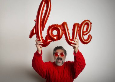 Beyaz arka planda aşk sözcüğü şeklinde bir balon tutan adamın portresi. Sevgililer Günü Kutlaması