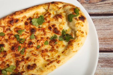 Tahta arka planda sarımsaklı ve tereyağlı ev yapımı naan ekmeği.