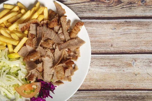 Patates kızartmalı biftek ve ahşap arka planda salata. Mesaj için yer var.
