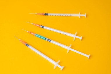Sarı arka planda tıbbi şırıngalar. Coronavirus konsepti, kendinizi koruyun..