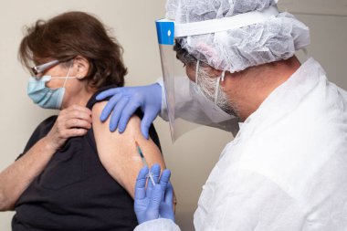 Muayene: Yaşlı kadın bir doktordan aşı olur.