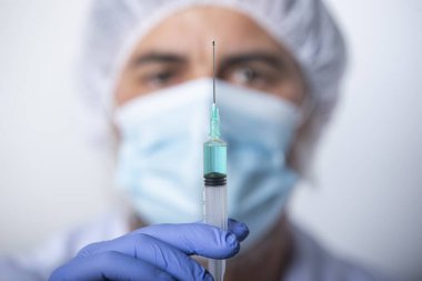 Doktor, hemşire, bilim adamı, araştırmacı elleri mavi eldivenli aşı için bir şırınga tutuyor..