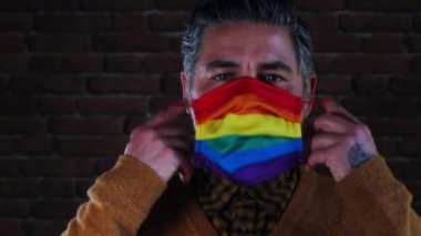 Bir adam LGBT bayrağıyla maske takıyor. Yakın plan portre.