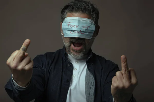 Angry man with eye mask showing middle finger gesture in protest.