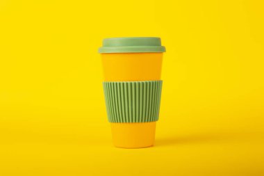 Sarı arka planda yeşil kapaklı kahve için ekolojik fincan. Sürdürülebilir yaşam tarzı. Ön görünüm.