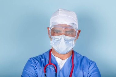 Mavi arka planda koruyucu maske ve gözlük takan doktor ya da hemşire..