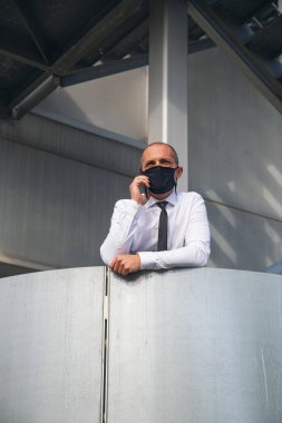 Businessman talking on the phone with face mask