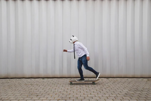 Geschäftsmann Skateboardet Auf Longboard Mit Pandabärmaske Gegen Graue Wand — Stockfoto