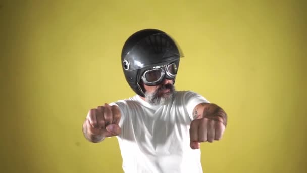 Homem Barbudo Com Capacete Simulando Dirigir Uma Motocicleta Fundo Amarelo — Vídeo de Stock