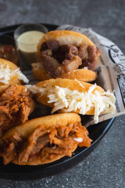 Farklı dilimlenmiş et ve peynirlerle dolu Latin amerikan arepalarını sunan tabaklar