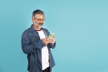 Cep telefonu kullanan, cihaz ekranına odaklanmış bakan bir adam