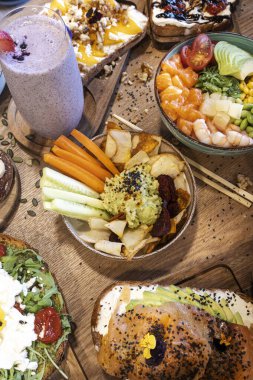 Poke kaseli lezzetli yemek, avokado tostu ve ahşap bir masada smoothie.