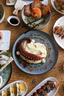 Ahtapot dokunaçları çeşitli Asya füzyon tabaklarıyla çevrili patates püresi yatağında servis ediliyor.