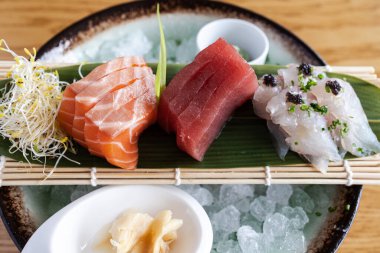 Taze dilimlenmiş sashimi porsiyonları ile buzda sunulan somon, ton balığı ve beyaz balık.
