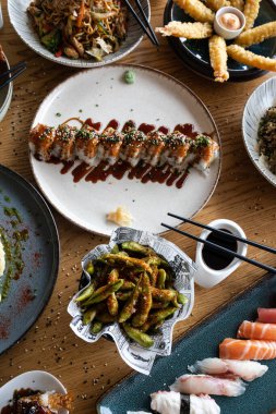 Asya yemekleri ahşap bir masaya renkli bir yemek serpiştiriyor.