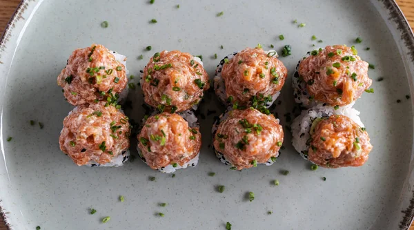 Sekiz somon tarçınlı suşi, siyah susamlı ve seramik tabakta soğan.