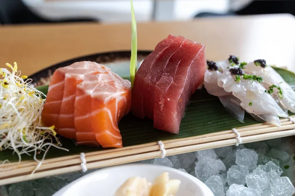 Bambu hasırında buzlu ve filizli taze çiğ balık saşimi parçaları.