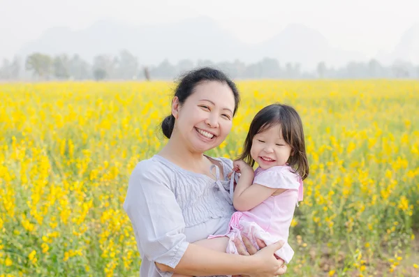 Мать и ребенок улыбаются на цветочном поле — стоковое фото
