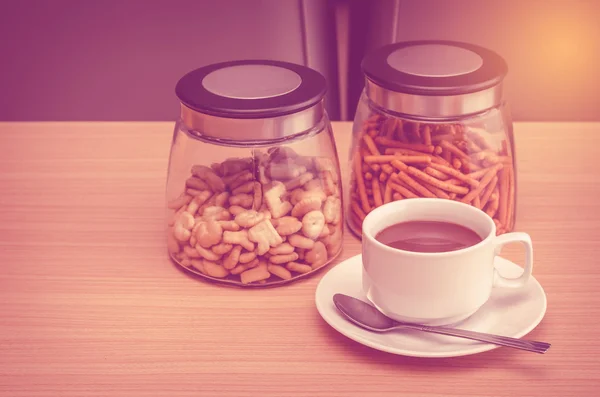 Кофейная чашка и закуски на деревянном столе — стоковое фото