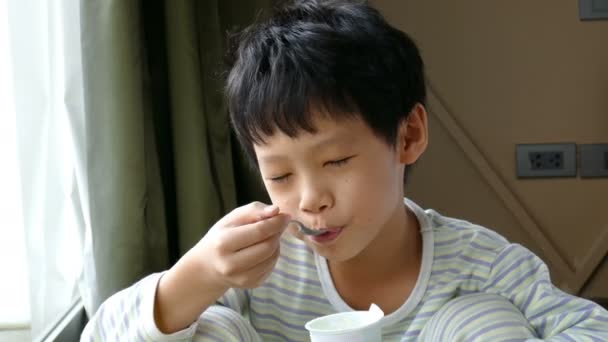 Niño comiendo yogur en casa — Vídeo de stock