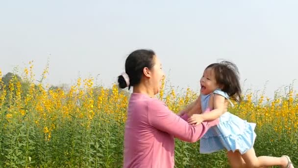 Mother and daughter spinning around in flower field — Stock Video