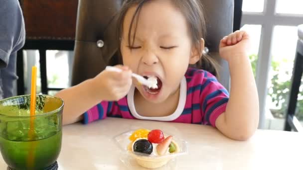 Chica comer una tarta de frutas dulces con una cuchara — Vídeo de stock