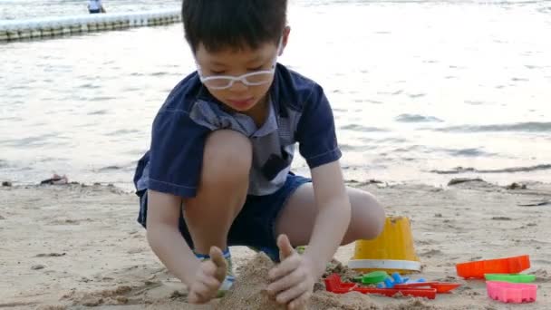 Niño juega en la arena en la playa — Vídeos de Stock