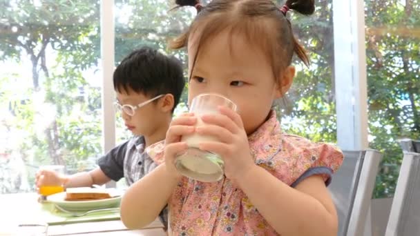 Niña sentada a la mesa y bebiendo leche — Vídeos de Stock