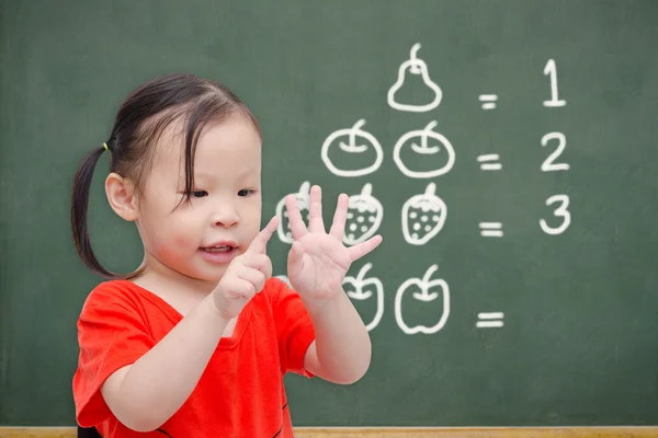 Meisje haar vinger in lettertype van schoolbord tellen — Stockfoto