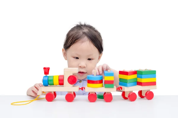 Girl playing with wooden train toy over white — Stock Photo, Image