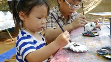 Asyalı Çocuklar bir heykelcik boyama . 