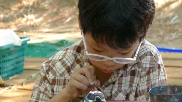 Niño asiático pintando una estatuilla  . — Vídeo de stock