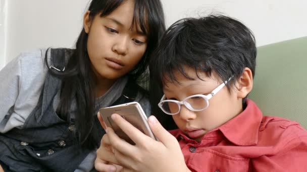 Niño y su hermana jugando juego en el teléfono inteligente — Vídeos de Stock