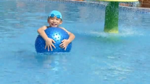 Garçon jouer à la balle dans la piscine — Video