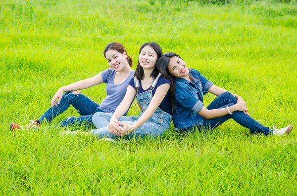 Drie vrouwen zitten in de weide en glimlach — Stockfoto