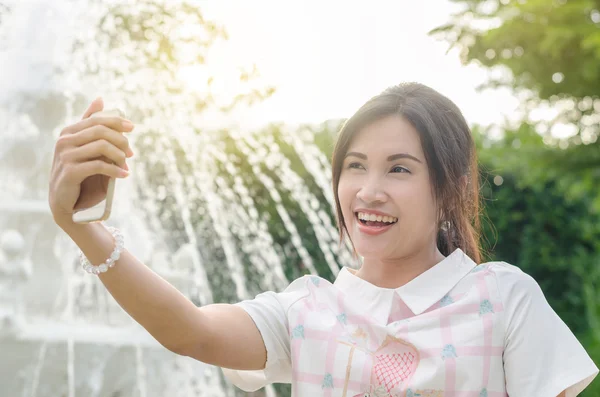Meisje dat haar foto neemt door slimme telefoon buiten — Stockfoto