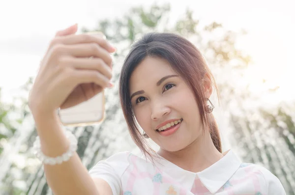 Meisje dat haar foto neemt door slimme telefoon buiten — Stockfoto