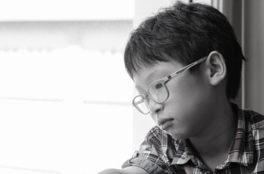 Üzgün çocuk pencereden dışarı bakıyor