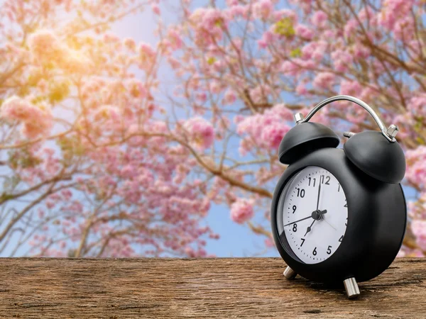 꽃 배경에서 위에 나무 테이블 시계 — 스톡 사진
