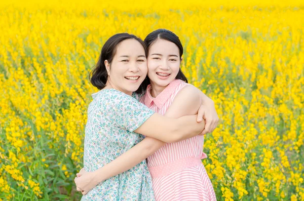 Moeder en haar dochter op het veld van de bloem — Stockfoto