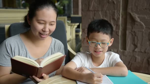 Мать учит своего сына делать домашнее задание — стоковое видео